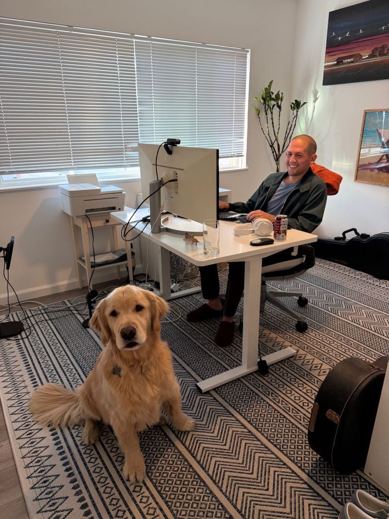 Aubrey at a desk with a golden retriever in a home office